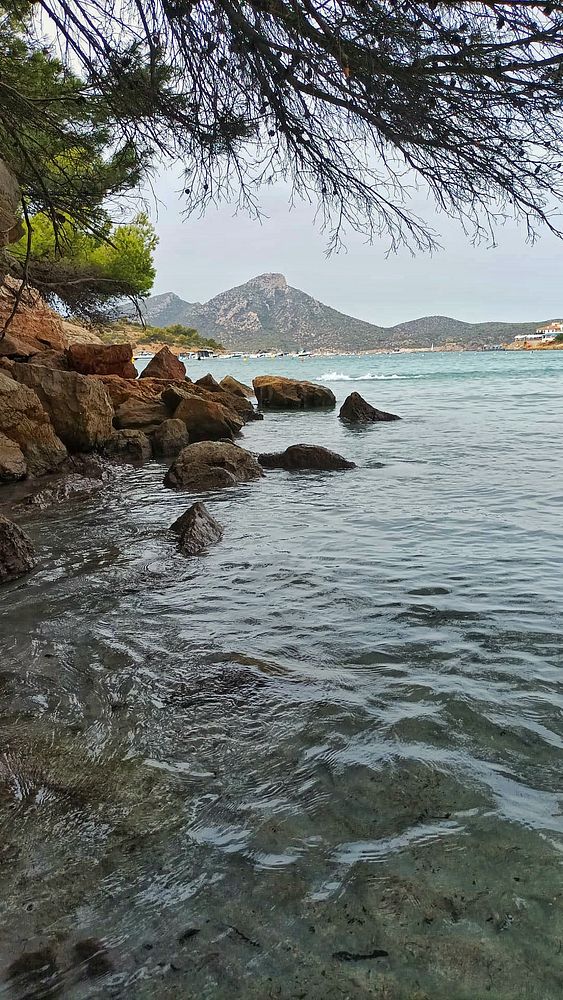 A serene beach scene featuring rocky shores and a cloudy sky.