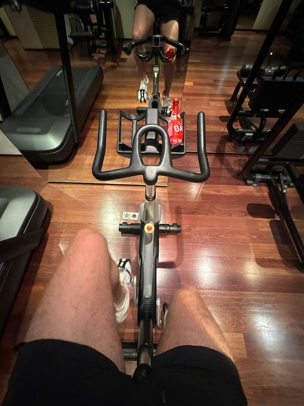 A person is exercising on a stationary bike in a gym setting.