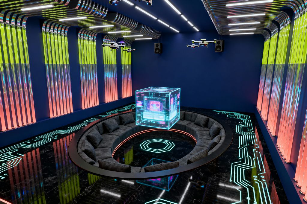 A futuristic media room with deep blue walls features a sunken circular charcoal sectional surrounding a glowing floor motif, while a translucent holographic cube display floats at center. The glossy black floor has teal circuit-trace lighting, ribbed acrylic wall panels glow in gradients from yellow‑green to coral, and chrome ceiling conduits with linear LEDs, wall-mounted speakers, and drone-like fixtures create an immersive neon-lit atmosphere.