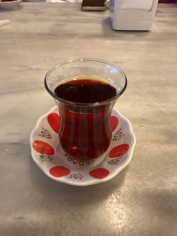 A glass of Turkish tea on a decorative saucer placed on a marble table.