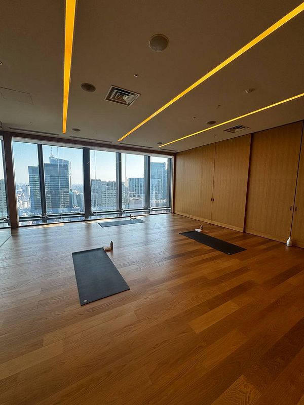 A spacious, modern Pilates studio with large windows offering a city view.
