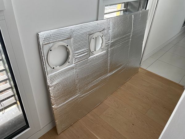DIY window insulation setup made from reflective and insulating materials installed on a window frame for supporting home air conditioning efficiency.
