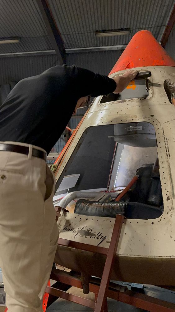 A person inspects a rocket capsule during a lab tour.