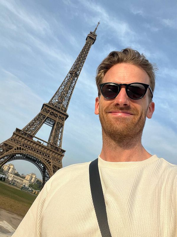 A man takes a selfie in front of the Eiffel Tower in Paris.