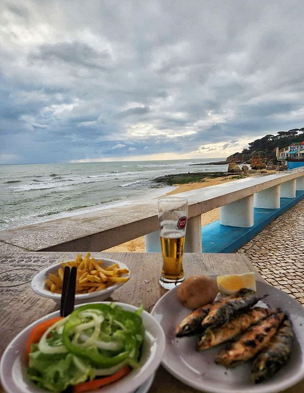 A scenic seaside dining experience featuring grilled fish and a view of the ocean.