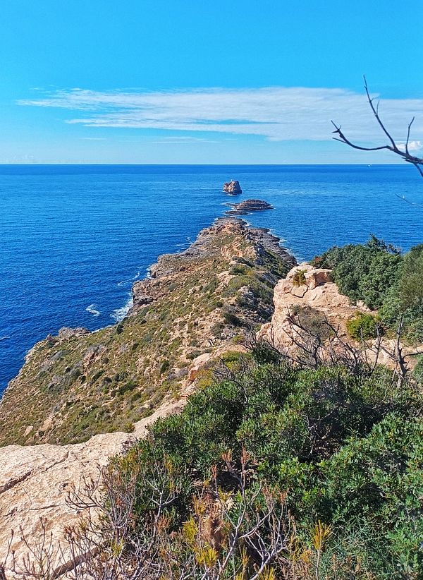 A scenic coastal view featuring a rocky outcrop extending into the ocean.