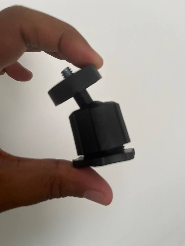 A hand holds a black tripod accessory.