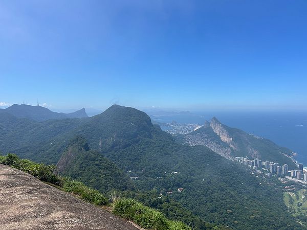 A panoramic aerial view showing a dense favela adjacent to towering modern skyscrapers under a partly cloudy sky.