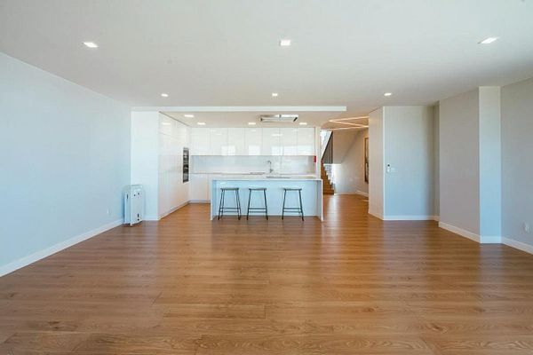 A spacious, modern kitchen and living area with minimal furnishings.