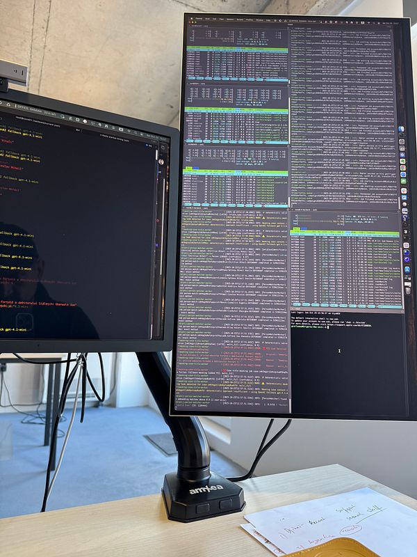 A dual-monitor setup in an office environment, featuring a vertical monitor displaying terminal outputs and a horizontal monitor with code.