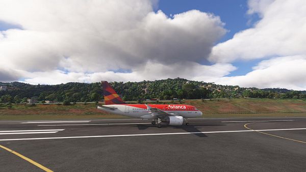An Avianca A318 aircraft is taxiing on a runway with a scenic backdrop.