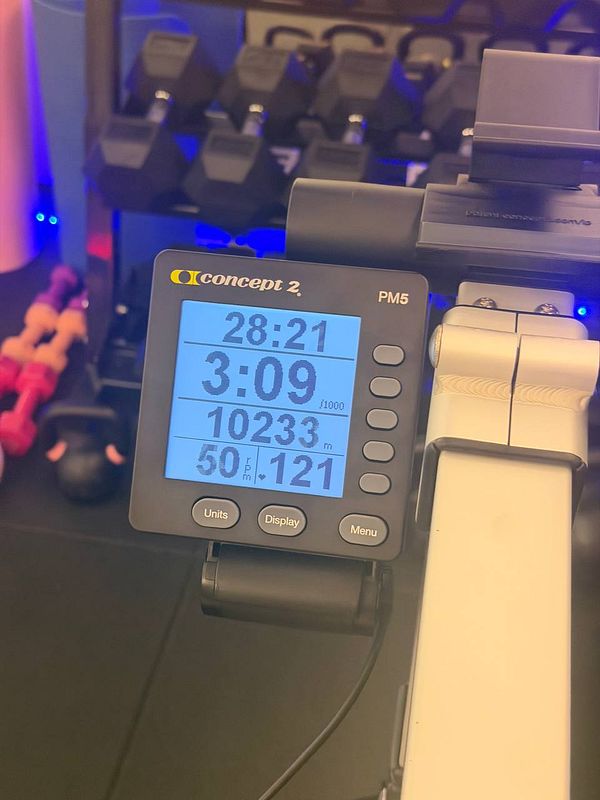 A person dressed in gym attire is walking indoors, carrying a small bag and wearing athletic shoes.