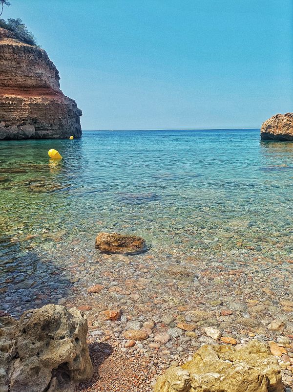 A serene coastal scene featuring clear water and rocky formations.