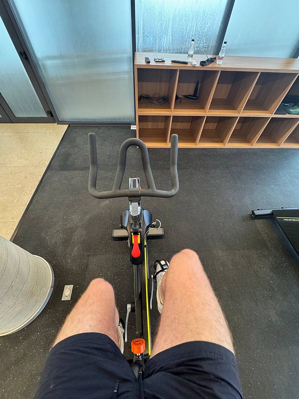 A person is seated on a stationary bike in a gym setting.