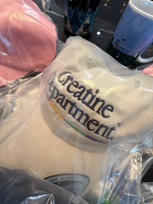 A collection of merchandise items, including a white cap and a pink cap, displayed in plastic packaging.