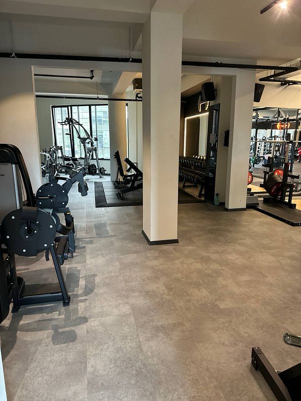 A modern gym interior featuring various workout equipment and a spacious layout.