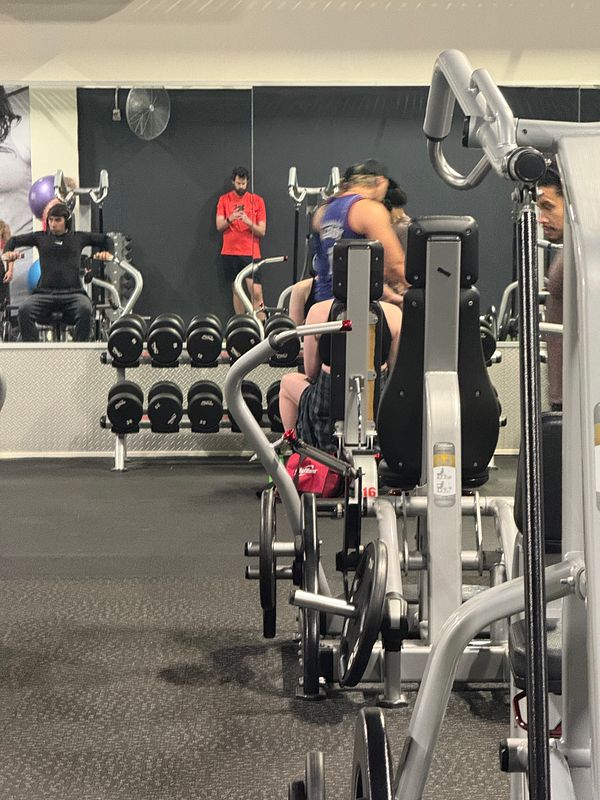 A gym scene featuring individuals engaged in various workouts.