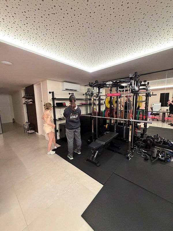 Black and white photo of a man lifting a heavy dumbbell in a gym, showcasing strength and determination.