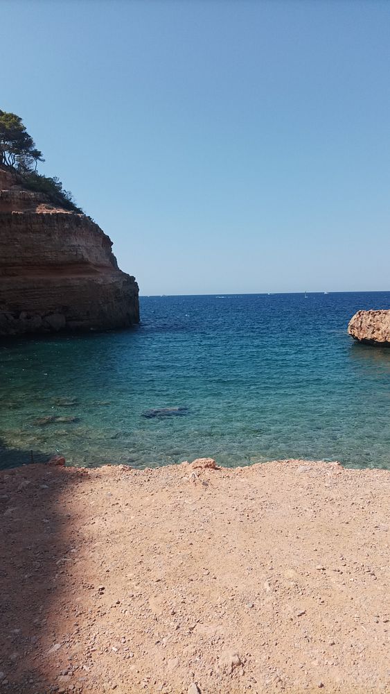 A serene coastal scene featuring clear blue water and rocky cliffs.