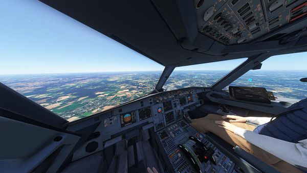 The image captures the cockpit view of an aircraft flying over a landscape.