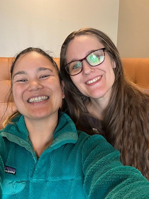 Two friends are smiling together in a cozy setting.