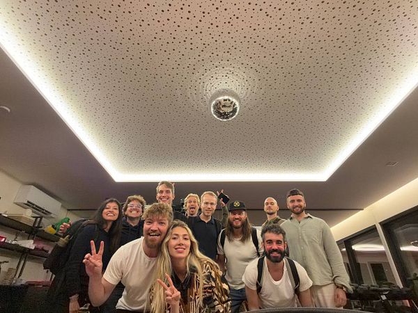 Group of eleven diverse young adults posing for a cheerful indoor photo under a modern ceiling with a disco ball.