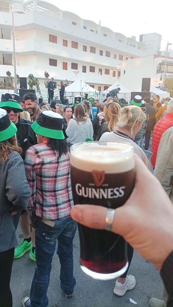 A green backdrop with St. Patrick's Day theme featuring a cartoon leprechaun, a pot of gold, and multiple shamrocks.