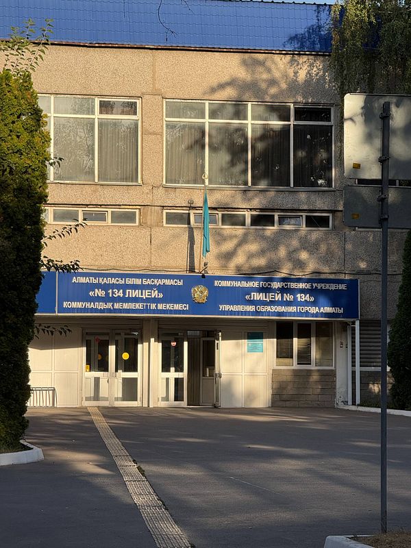 Photograph of the exterior entrance of a vocational high school building with red and gray facade and multiple windows.