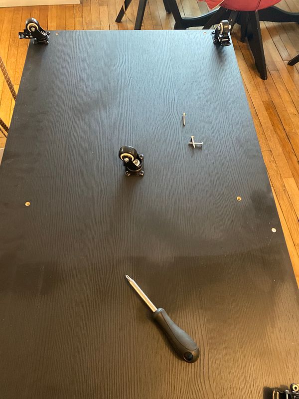 A work surface with furniture components and tools for assembly.