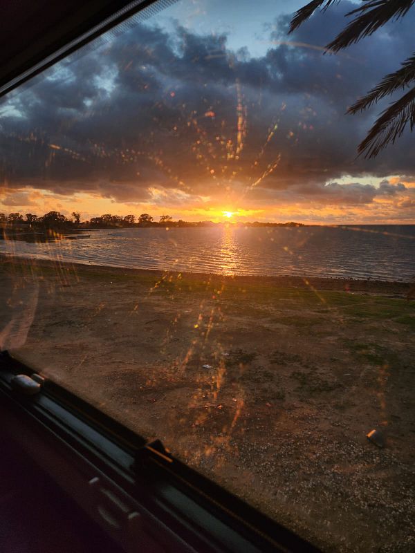A beautiful sunset view over a body of water, seen through a vehicle window.