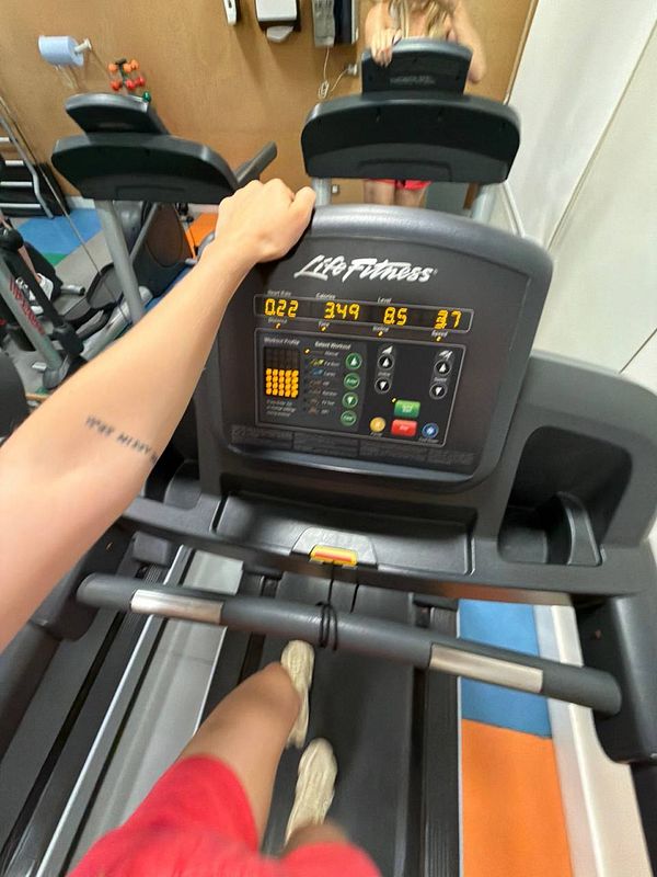 A woman in workout attire performing an exercise with a kettlebell in a gym setting.
