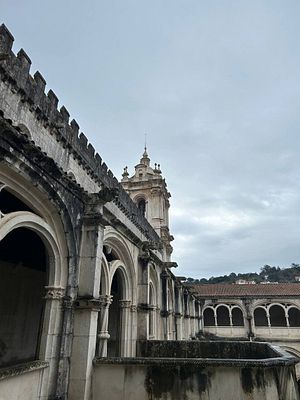 A historic monastery in Portugal with intricate architecture under a cloudy sky.