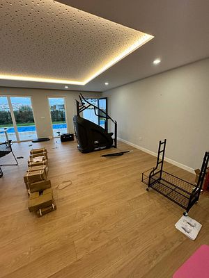 A partially set up home gym space featuring fitness equipment and unpacked boxes.