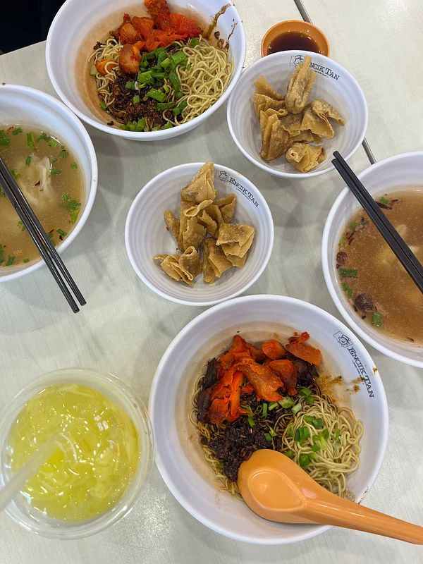 A variety of Asian dishes are arranged on a table, including noodles, soup, and snacks.