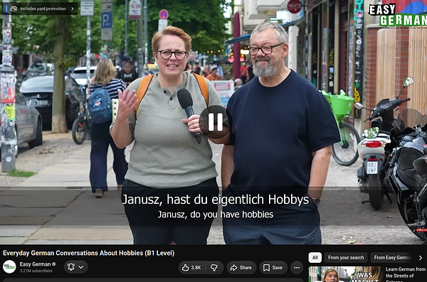 A MacBook Air screen displays a video of a woman accompanied by German subtitles, with the Twitter interface visible.