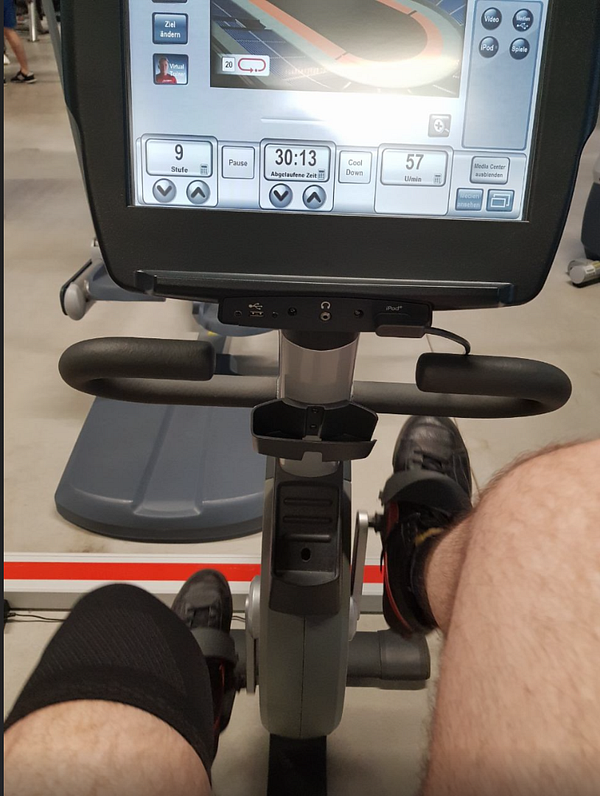 A person is exercising on a stationary bike in a gym setting.