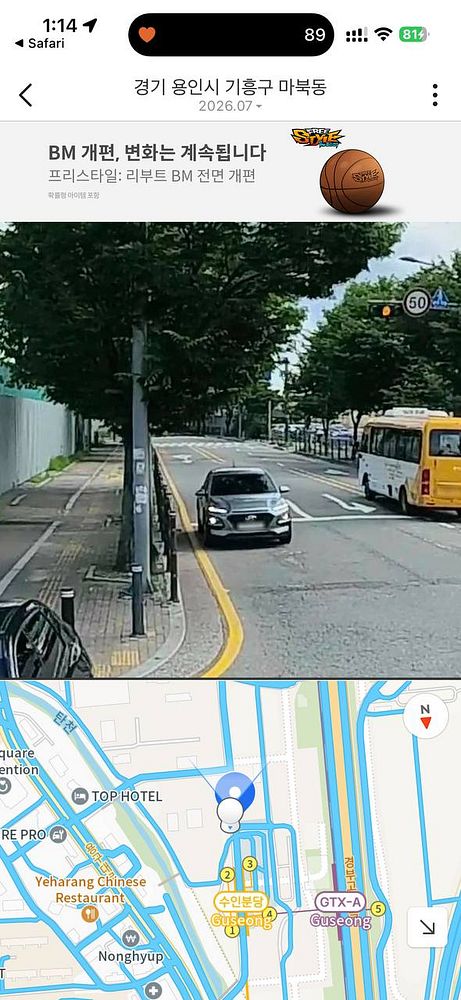 Street view image of a white car parked on the side of a vibrant Korean street with various storefronts and signage.