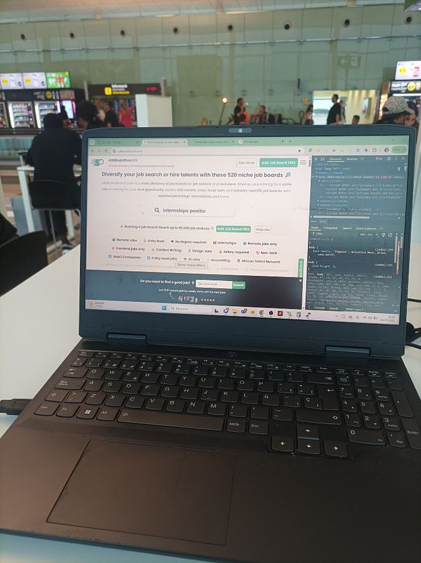 A laptop is open at a table in Barcelona airport, displaying a job board website.