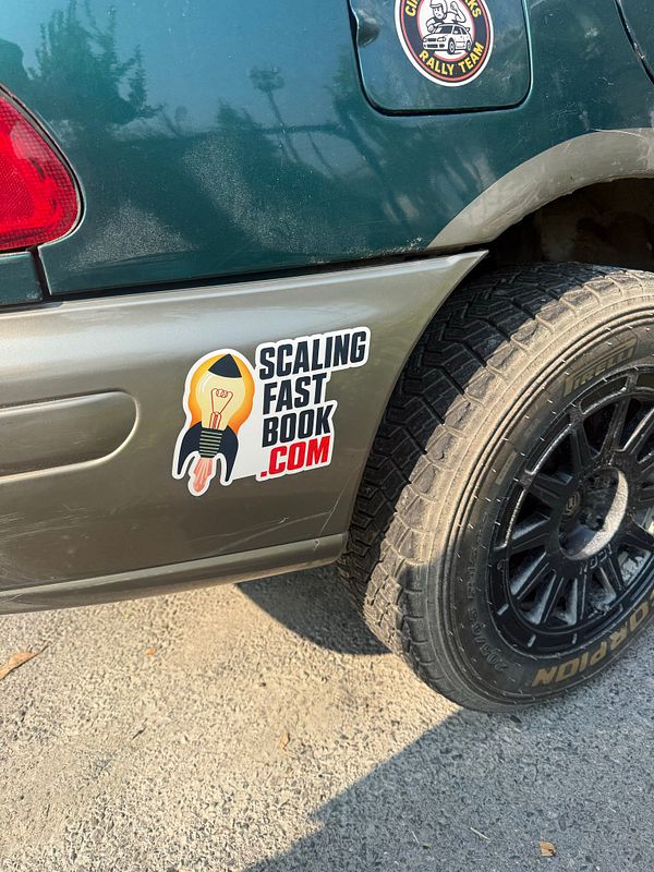Close-up of a rally car's front bumper featuring a 'Code Refactoring' sticker alongside various sponsor logos.