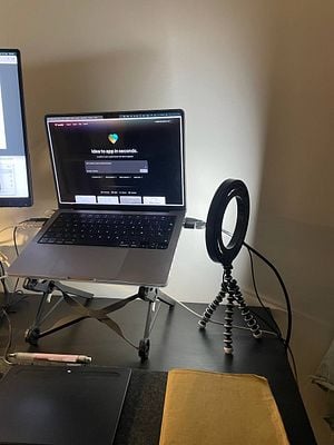 A workspace setup featuring a laptop, a ring light, and a drawing tablet.