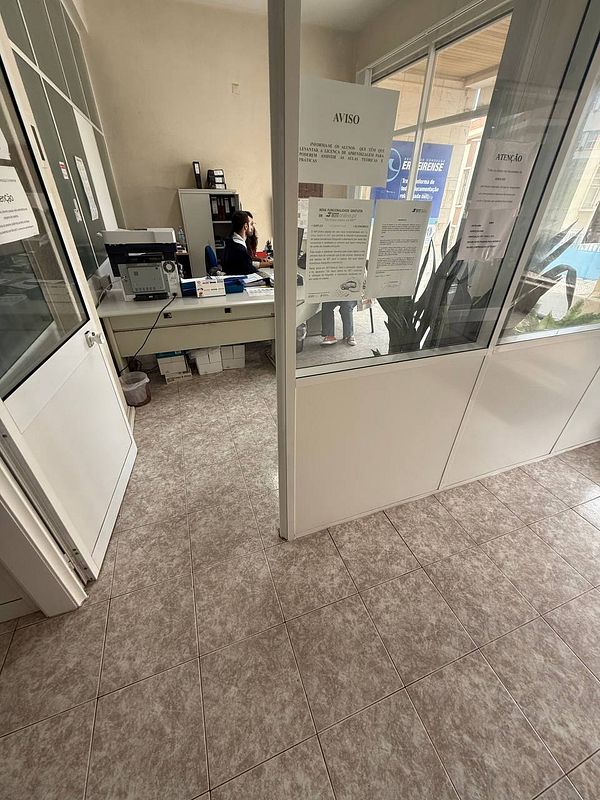 The image depicts the interior of a driving school office with a receptionist at a desk.