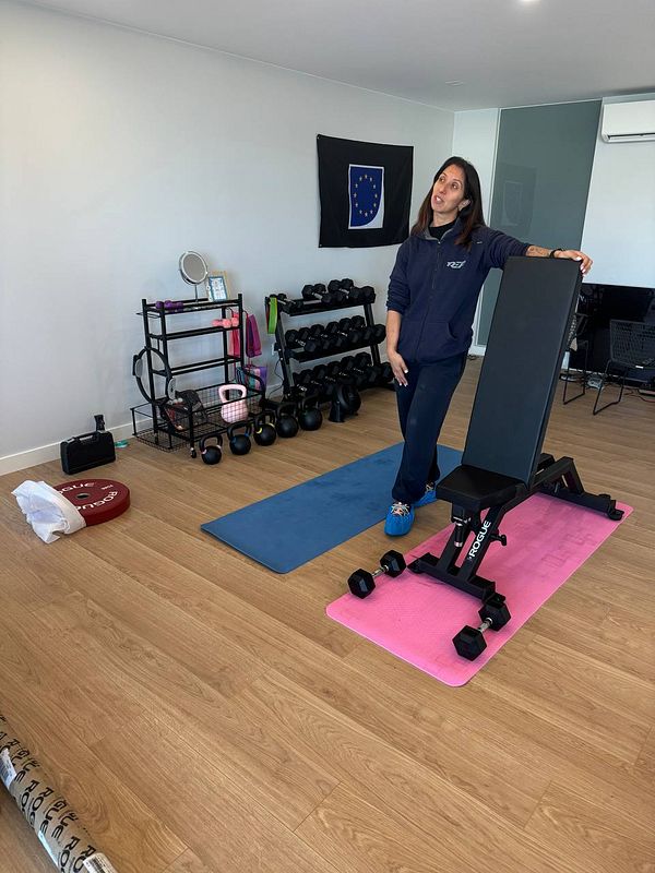 A personal trainer stands in a home gym, ready for a workout session.