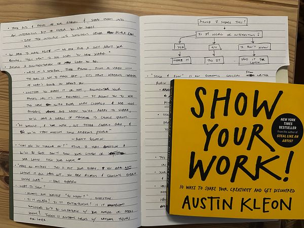 A notebook filled with handwritten notes alongside the book 'Show Your Work!' by Austin Kleon.