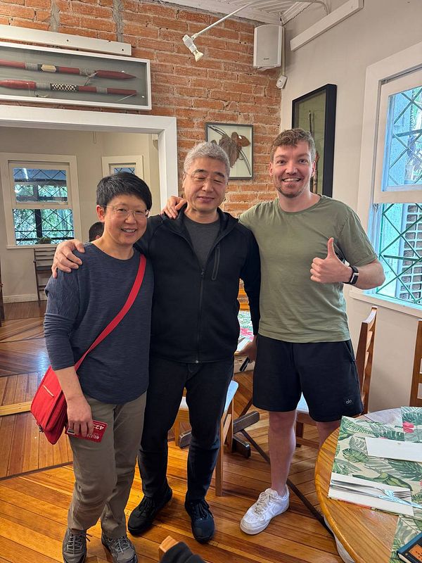 Three individuals pose together in a cozy indoor setting.