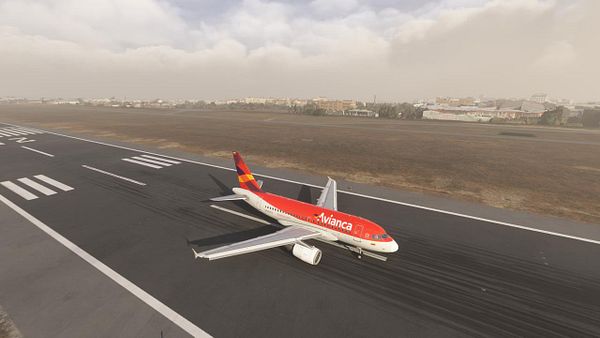 An Avianca A318 aircraft is taxiing on a runway with a cityscape in the background.