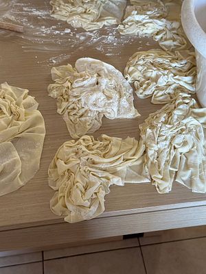 A messy kitchen countertop covered with crumpled pie dough and flour.