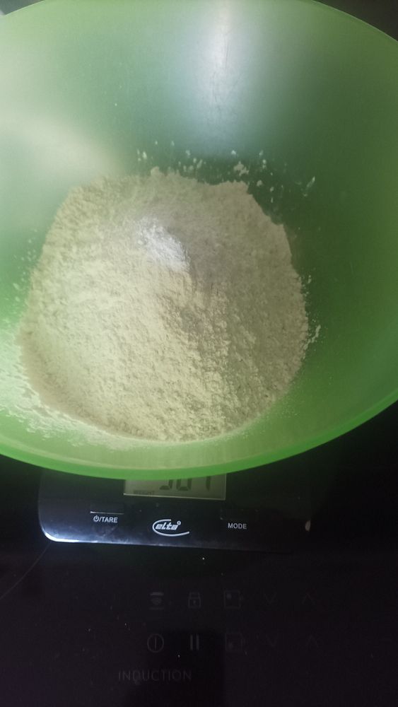 A bowl of flour is placed on a digital scale, indicating a weight measurement.