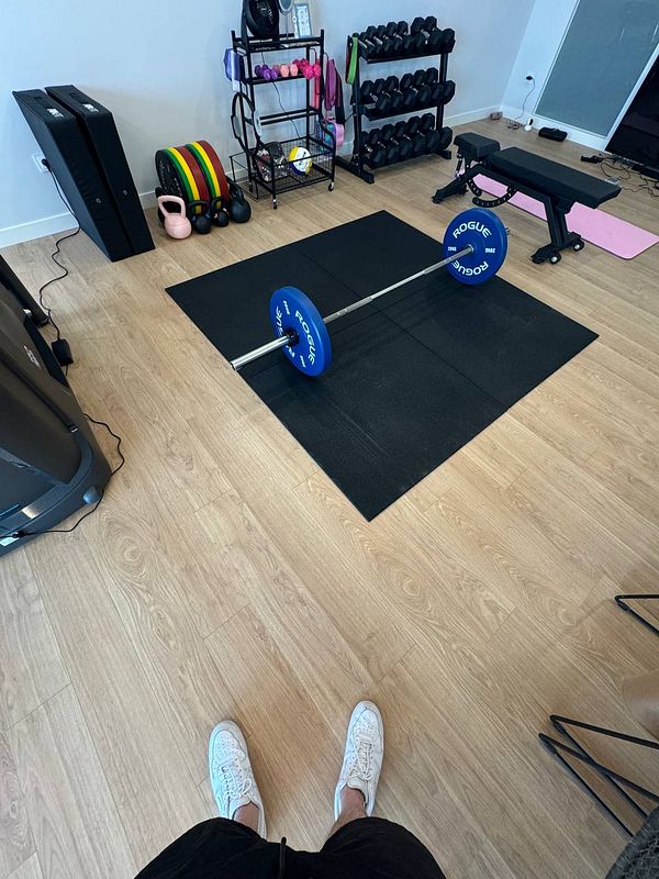 A home gym setup featuring a barbell, weights, and various fitness equipment.