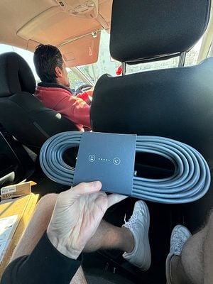 A person is holding a Starlink cable package inside a vehicle while a driver is visible in the front seat.