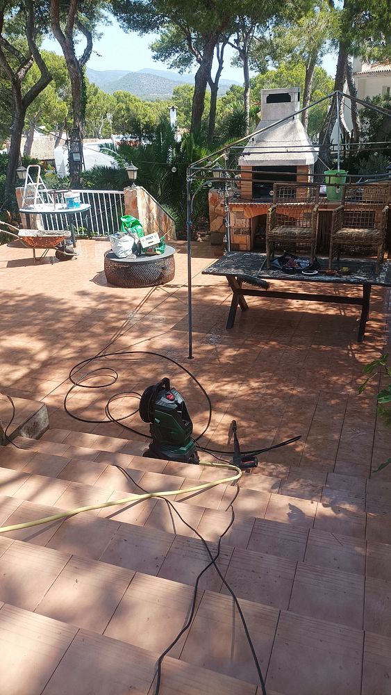A terrace area is being prepared for cleaning, featuring various outdoor furniture and equipment.